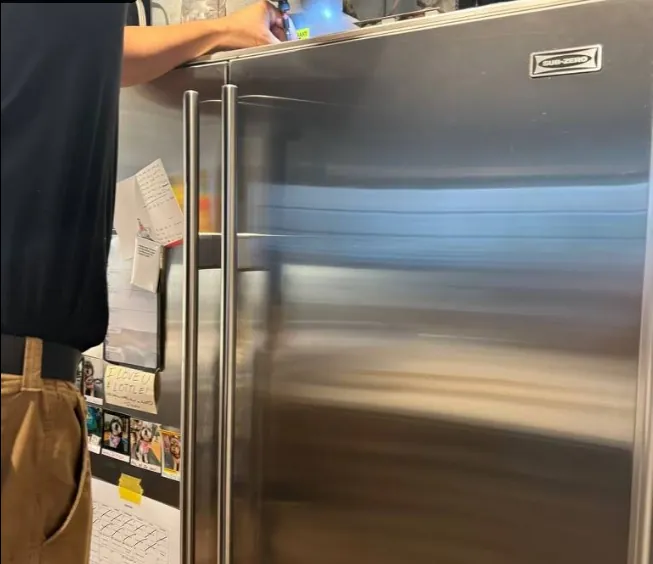 Built-in refrigerator being serviced in a home kitchen